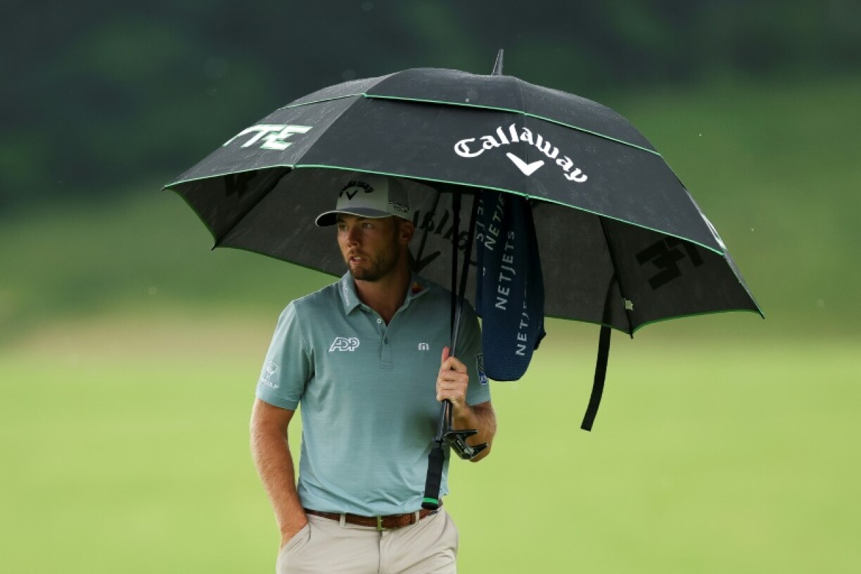 US Open leader Sam Burns of the United States waited under his umbrella as heavy rain halted the 125th US Open after he had completed seven holes in the final round