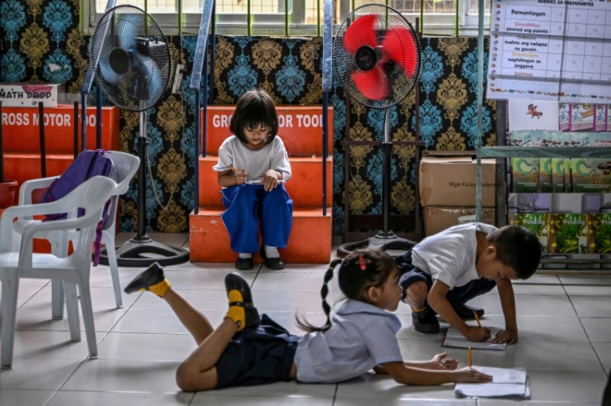 Students working on activities next to fans at an elementary school at Baseco in Manila on March 21