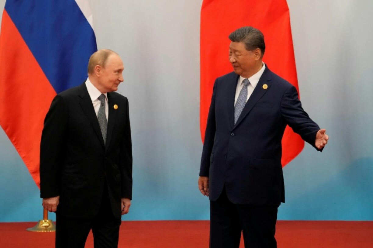 Chinese President Xi Jinping shows the way to Russian President Vladimir Putin after the photo session of the Shanghai Cooperation Organization Summit in Tianjin