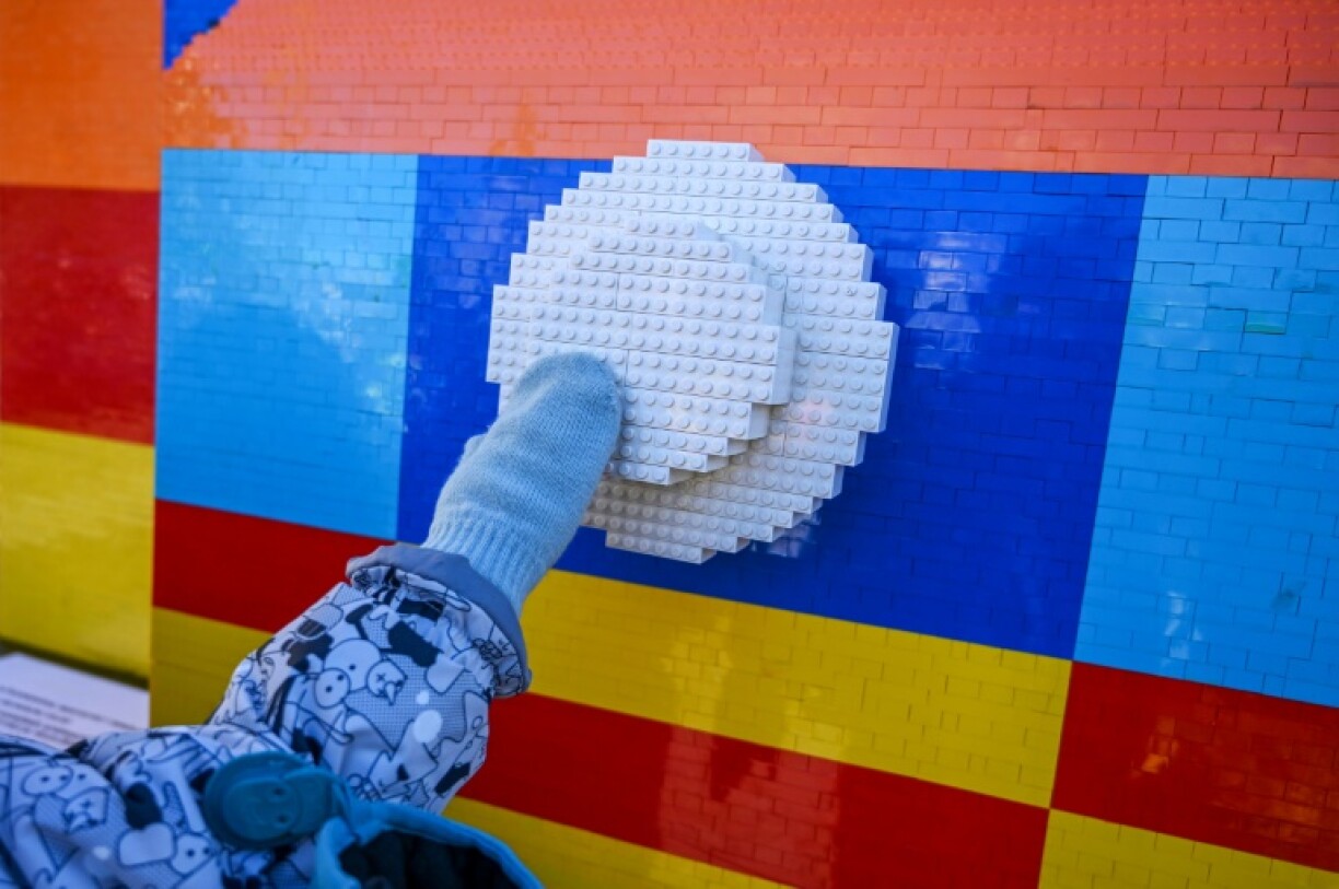A child reaches out to touch the Lego tram