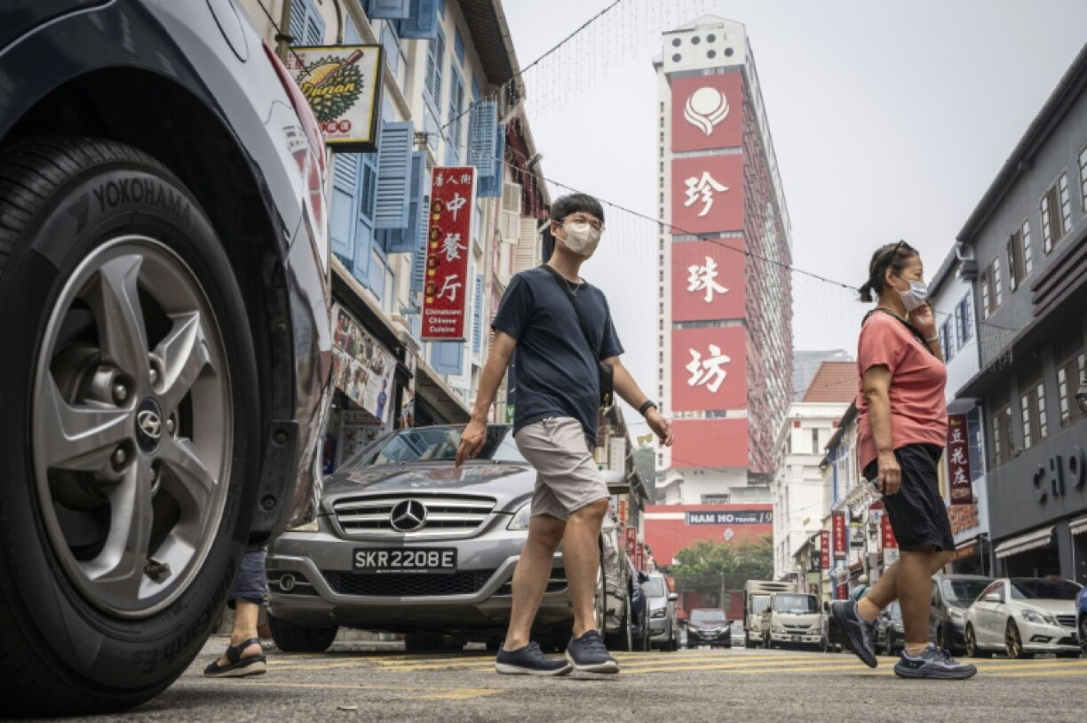 People wearing face masks cross a street in Singapore's Chinatown on as the country continues to be shrouded in haze caused by fires in Indonesia