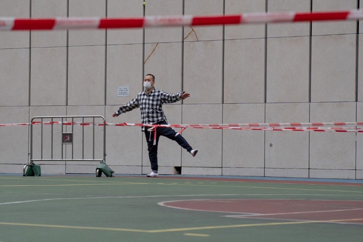 A man exercises outside a roped-off basketball court, closed due to Covid-19 social distancing restrictions, in the Mongkok area of Hong Kong on February 5, 2022