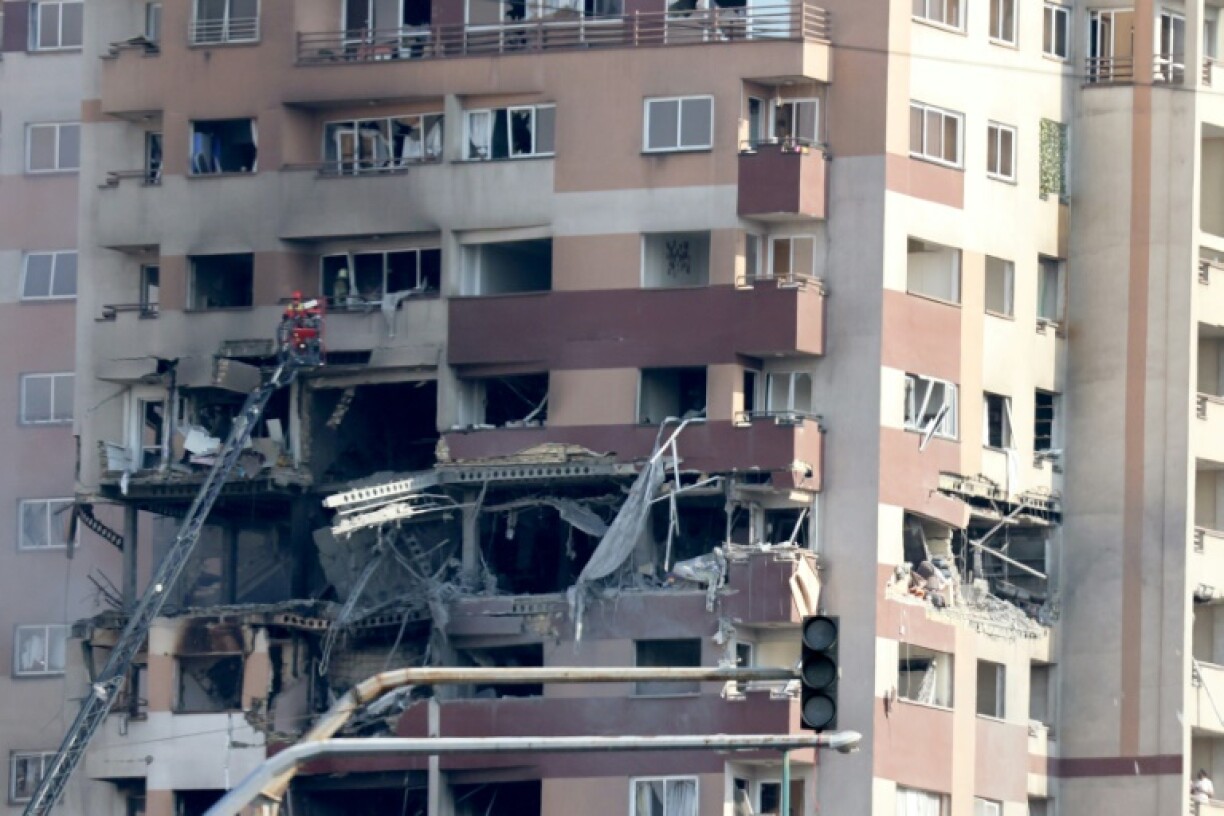 Rescue teams work outside a building targeted by an Israeli strike in the Iranian capital Tehran