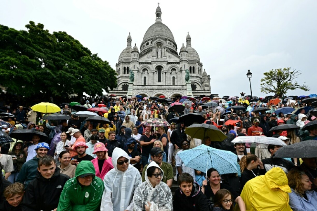 Spectators gather under umbrellas as they await the arrival of the Tour de France riders at the Sacre-Coeur basilica in Montmartre