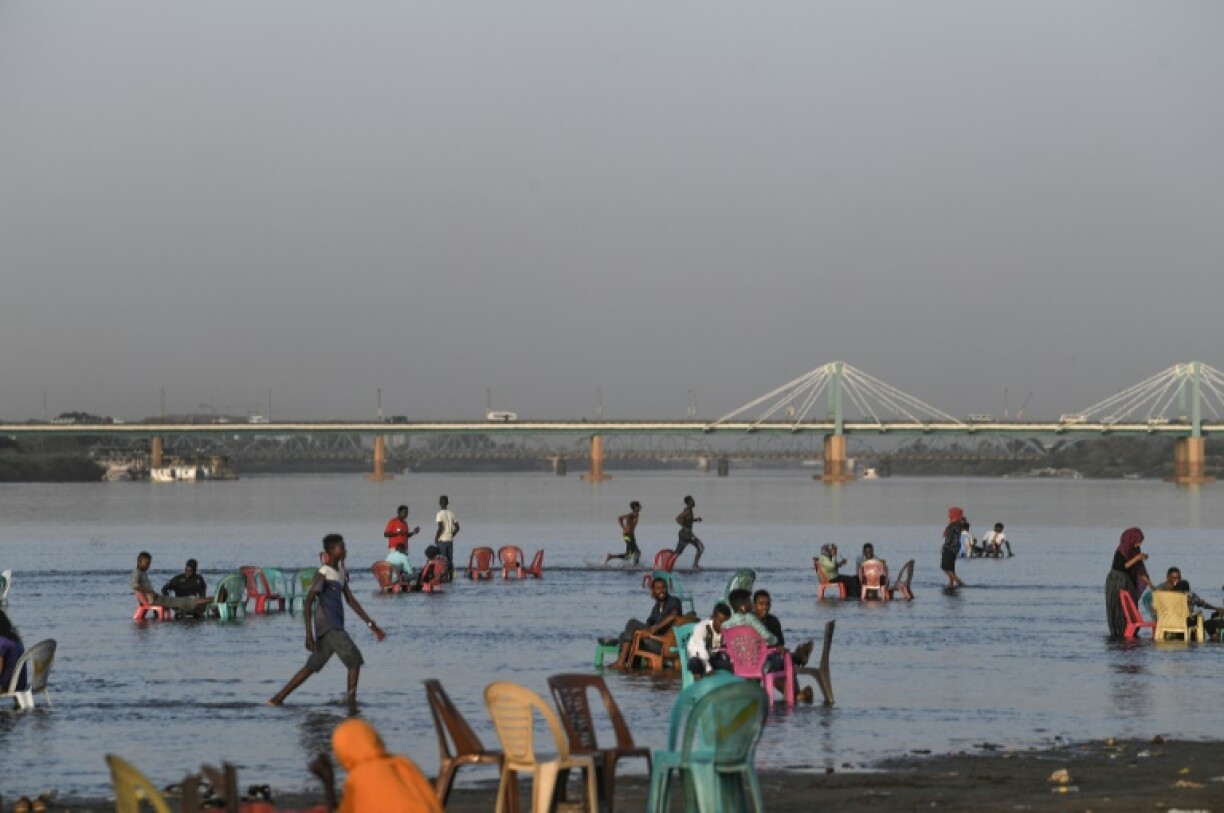 In this file picture from before the war, families gather by the shallow waters of the Nile River at the Tuti island