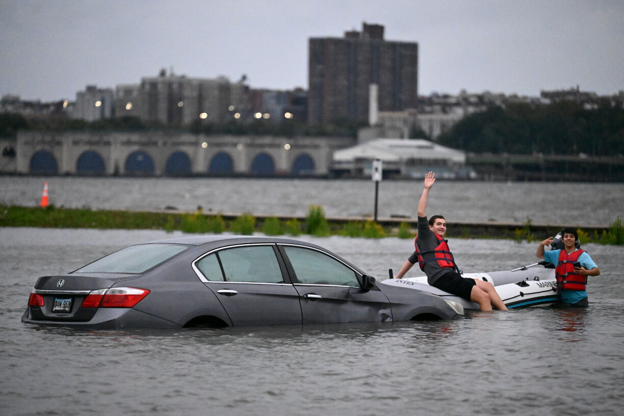 Une personne est aperçue sur un bateau près d'un véhicule submergé par les eaux de crue sur un parking le long du fleuve Hudson lors d'une tempête du nord-est à Edgewater, dans le New Jersey.