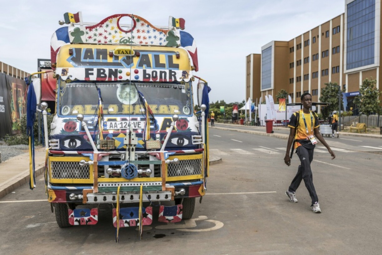 A volunteer walks past a typical Senegalese 'car rapide' at the Youth Olympic Village