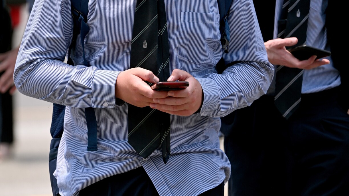 A schoolboy looks at his phone in Melbourne on 27 November as Australia looks to ban children under 16 from social media with claims social media platforms have been tarnished by cyberbullying, the spread of illegal content, and election-meddling claims.