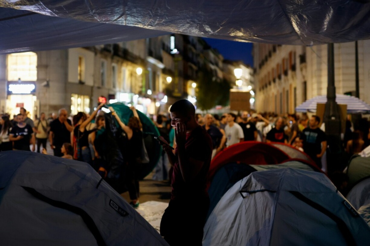Un manifestant regarde son téléphone à côté de tentes dans le campement en établi en protestation contre les expulsions et la crise du logement sur la Puerta del Sol, à Madrid, le 27 septembre 2026