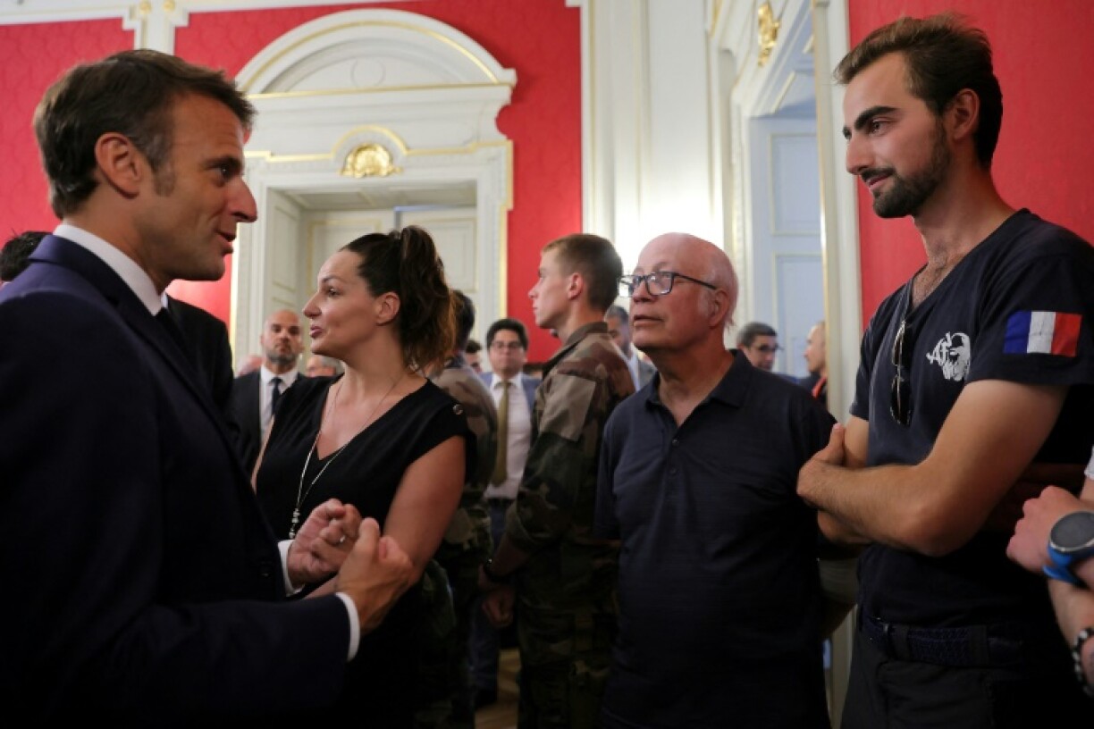 Le président français Emmanuel Macron (g) discute avec Henri, 24 ans (d), qui a tenté d'arrêter l'homme qui a attaqué la veille plusieurs personnes dans un parc d'Annecy, en préfecture de Haute-Savoie, le 9 juin 2023