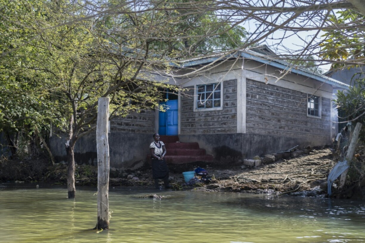 Faith Mpayei, 40 ans, se tient le 28 juillet 2026 à Marigat, au Kenya, devant sa maison, dont l'eau approche du perron après avoir quasiment submergé ce qui était une parcelle de deux hectares