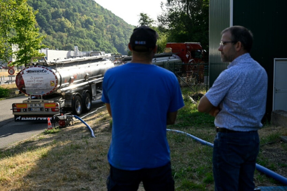 Xavier Barbin, directeur adjoint du Syndicat des eaux et de l'assainissement (SDEA) Centre-Alsace, à droite, discute avec employé du SDEA pendant qu'un camion-citerne ravitaille en eau la commune de Sainte-Marie-aux-Mines, dans le Haut-Rhin, le 11 août 2026