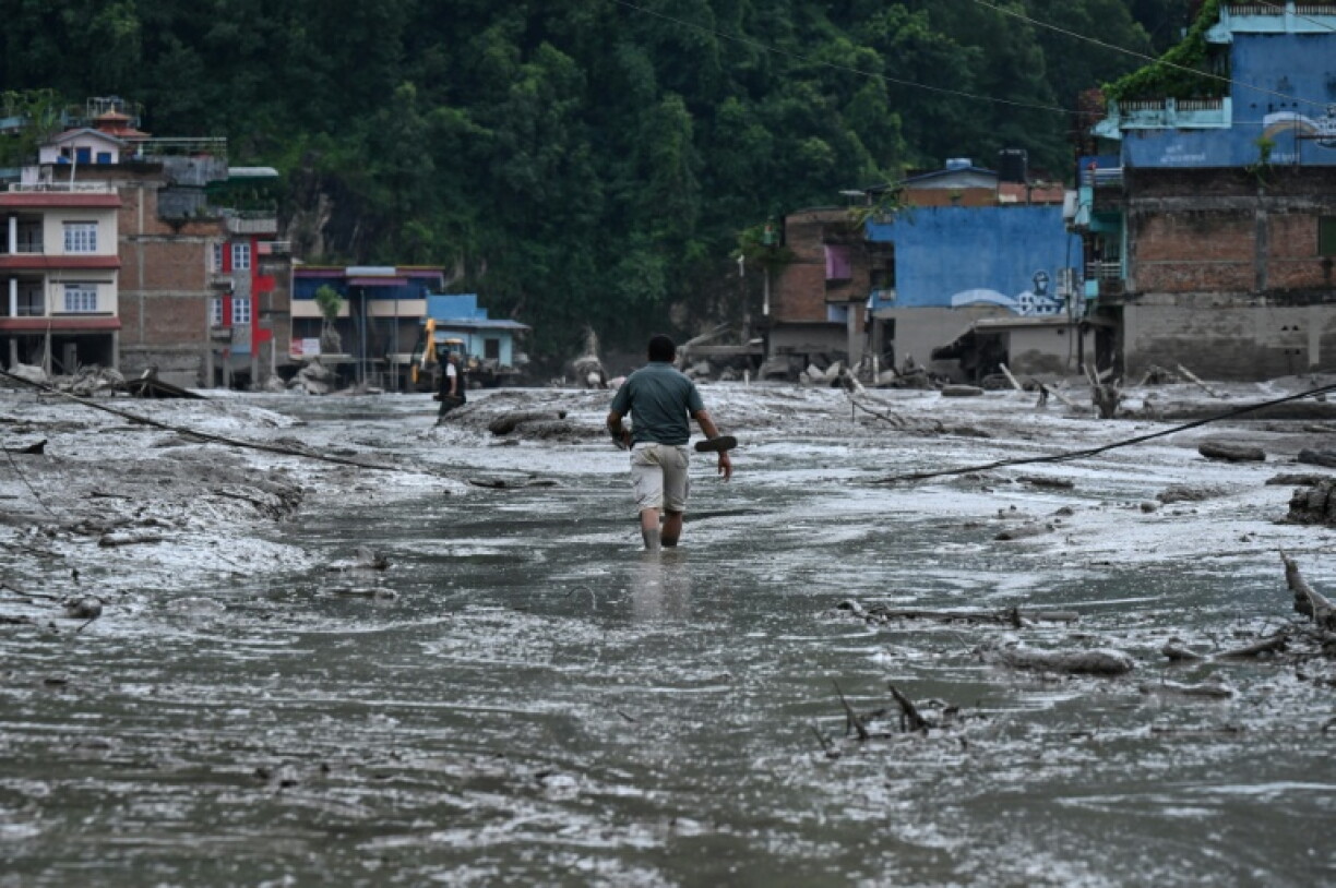 Un habitant marche dans une rue inondée de boue à Devighat, dans le district de Nuwakot au Népal, le 26 août 2026