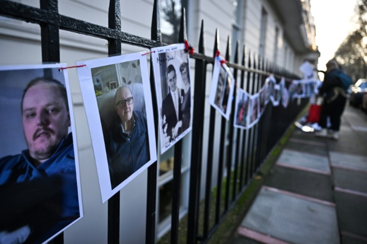 Des photos de victimes de Covid-19 posées sur une grille à l'extérieur du bâtiment où se déroule l'enquête publique Covid, le 6 décembre 2023 à Londres