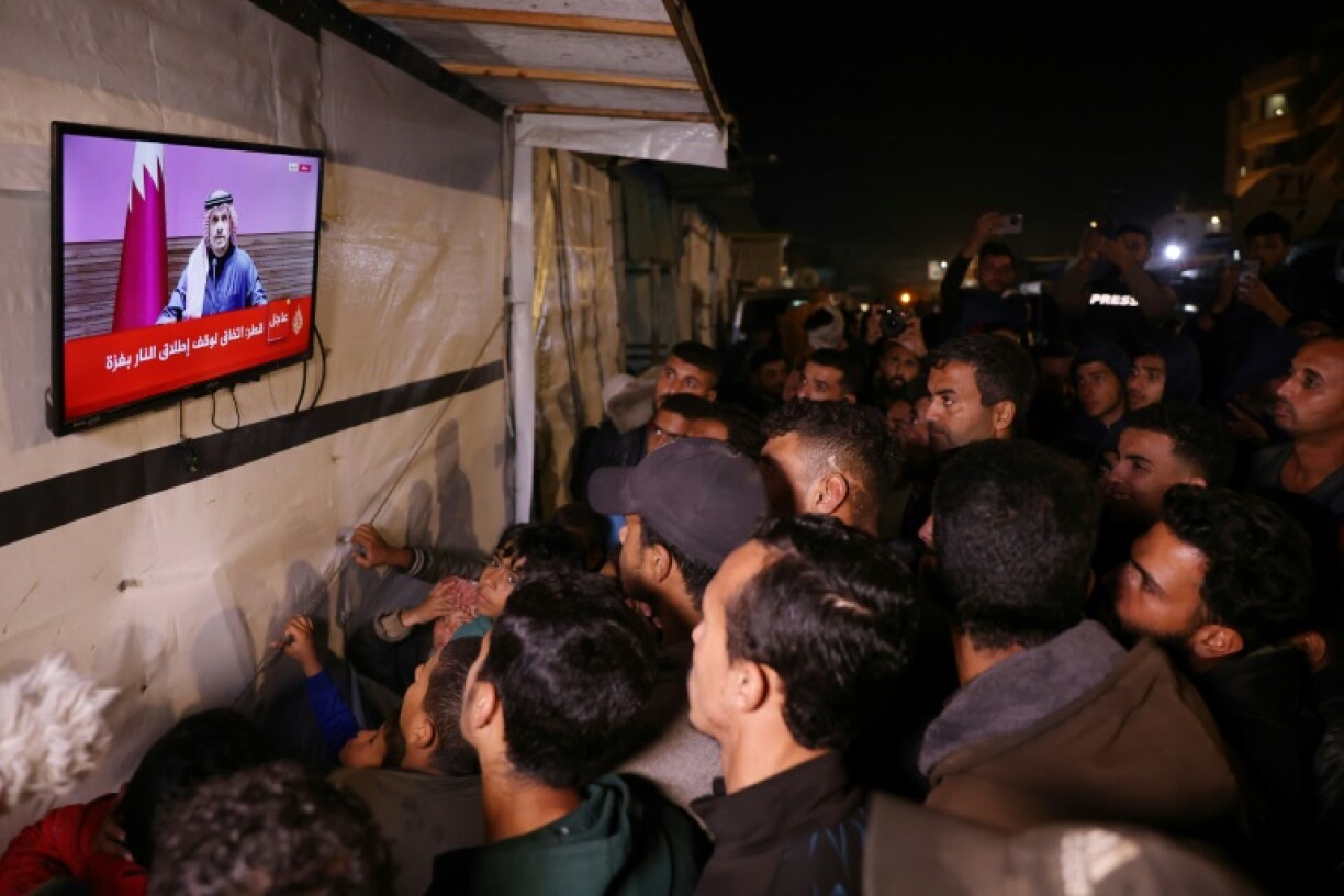 Des Palestiniens regardent à la télévision une conférence de presse du Premier ministre du Qatar, Mohammed ben Abdelrahmane Al-Thani, dans une rue de Khan Younès dans le sud de la bande de Gaza, le 15 janvier 2025