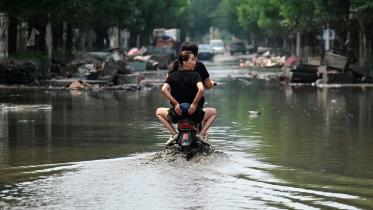 Des habitants de Zhuozhou en scooter dans l'eau, après de fortes pluies qui ont provoqué des inondations dans la province du Hebei, le 9 août 2023