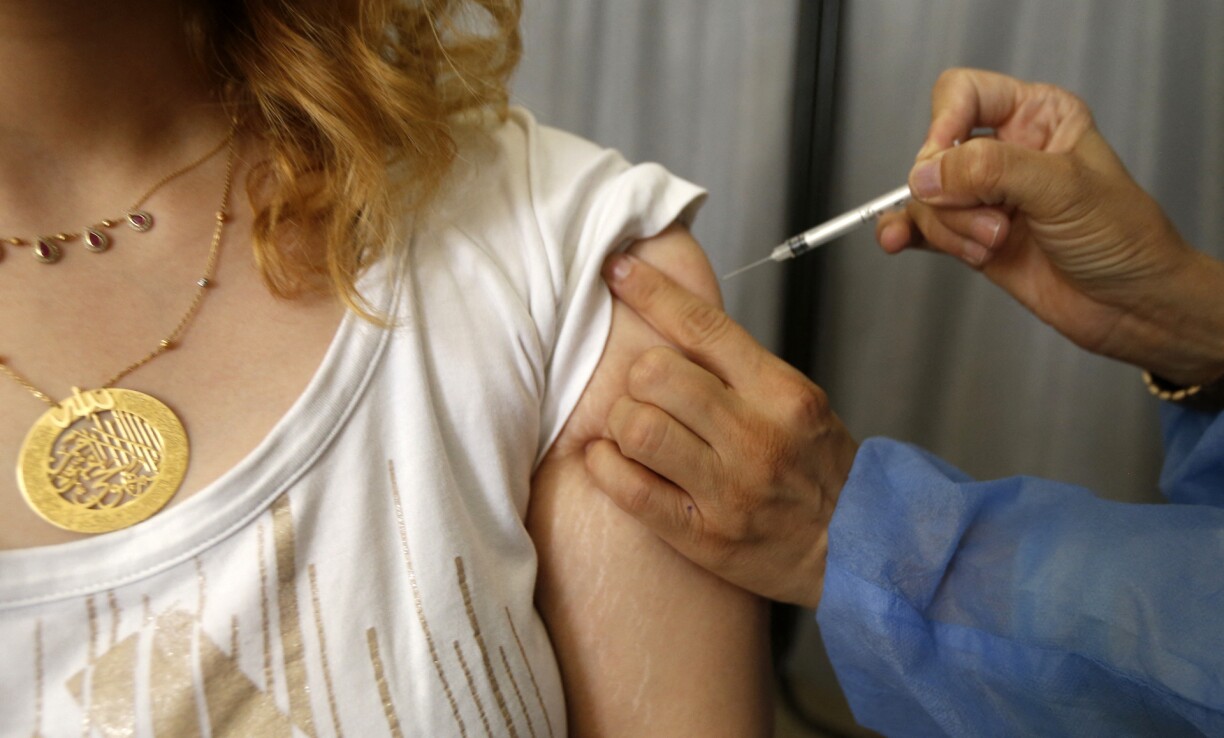 A Syrian health worker inoculates a woman with the AstraZeneca vaccine against the coronavirus in the capital Damascus, on September 9, 2021.