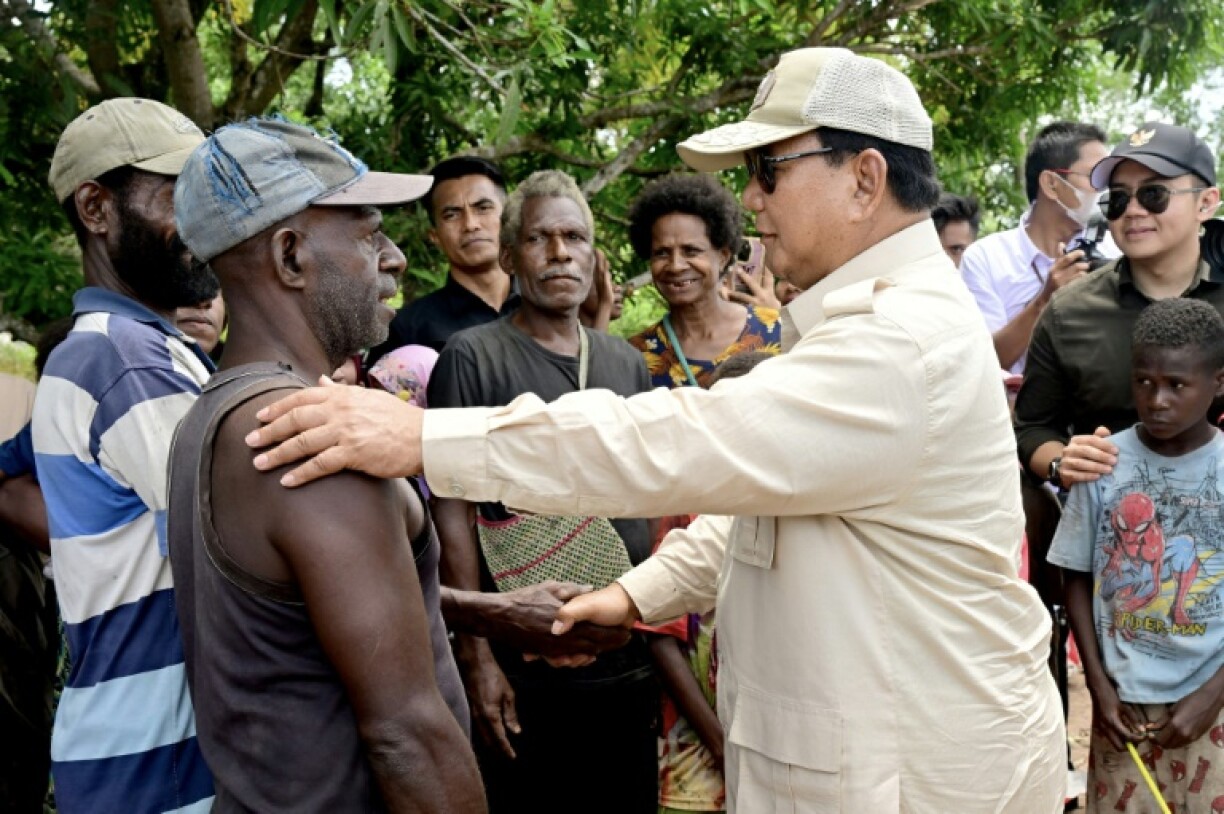 Indonesia's President Prabowo Subianto (R) speaking with locals during his visit to an agriculture programme site at Wanam village in Merauke