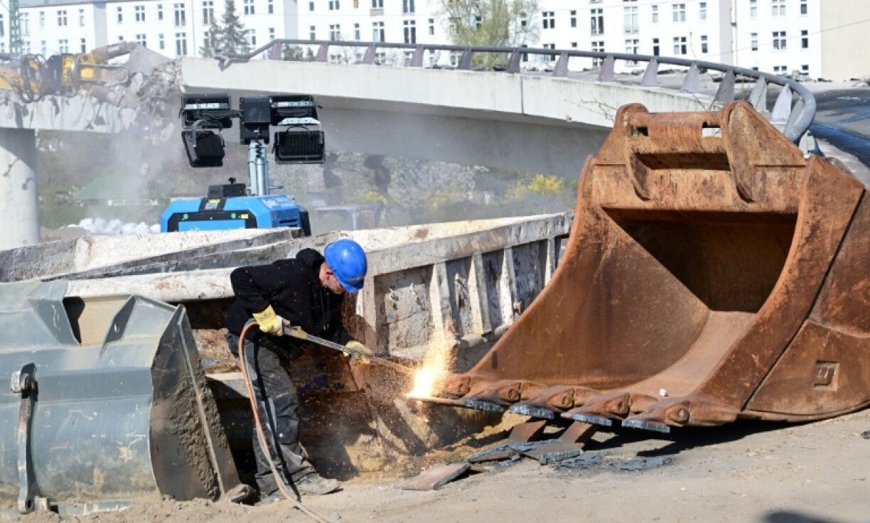 A construction worker welds part of an excavator as a bridge is being torn down in Berlin’s Charlottenburg district