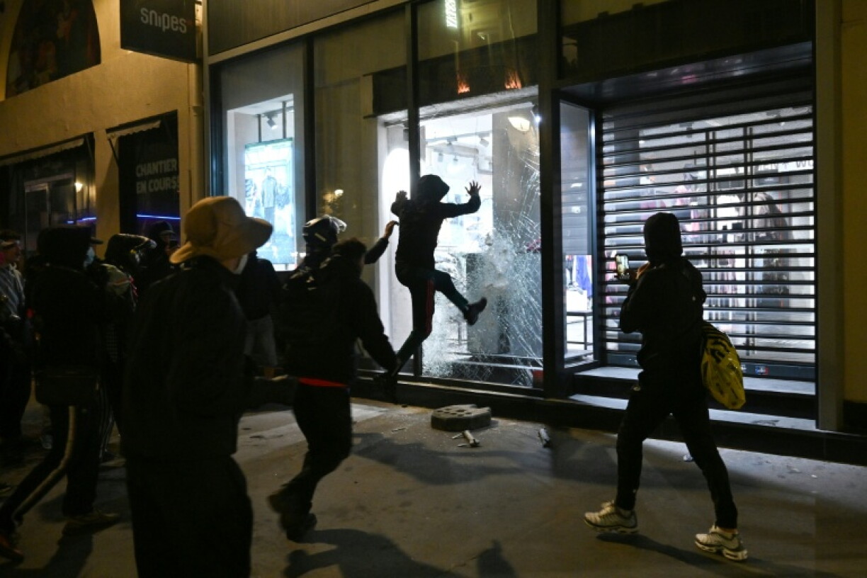 People try to destroy the window of a store in central Paris as clashes erupted at Place de la Republique following an unauthorised demonstration