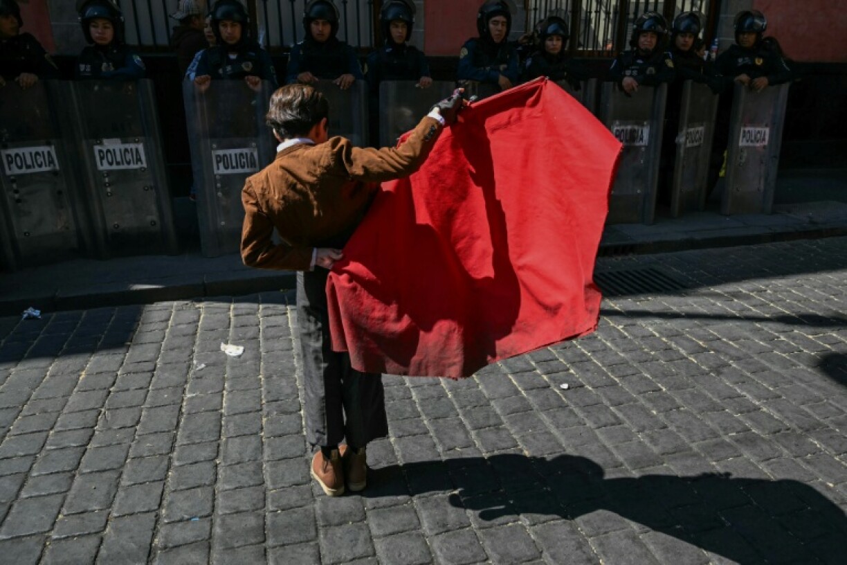 A young bullfighter performs in front of riot police during a protest against moves to ban killing or wounding bulls in Mexico City