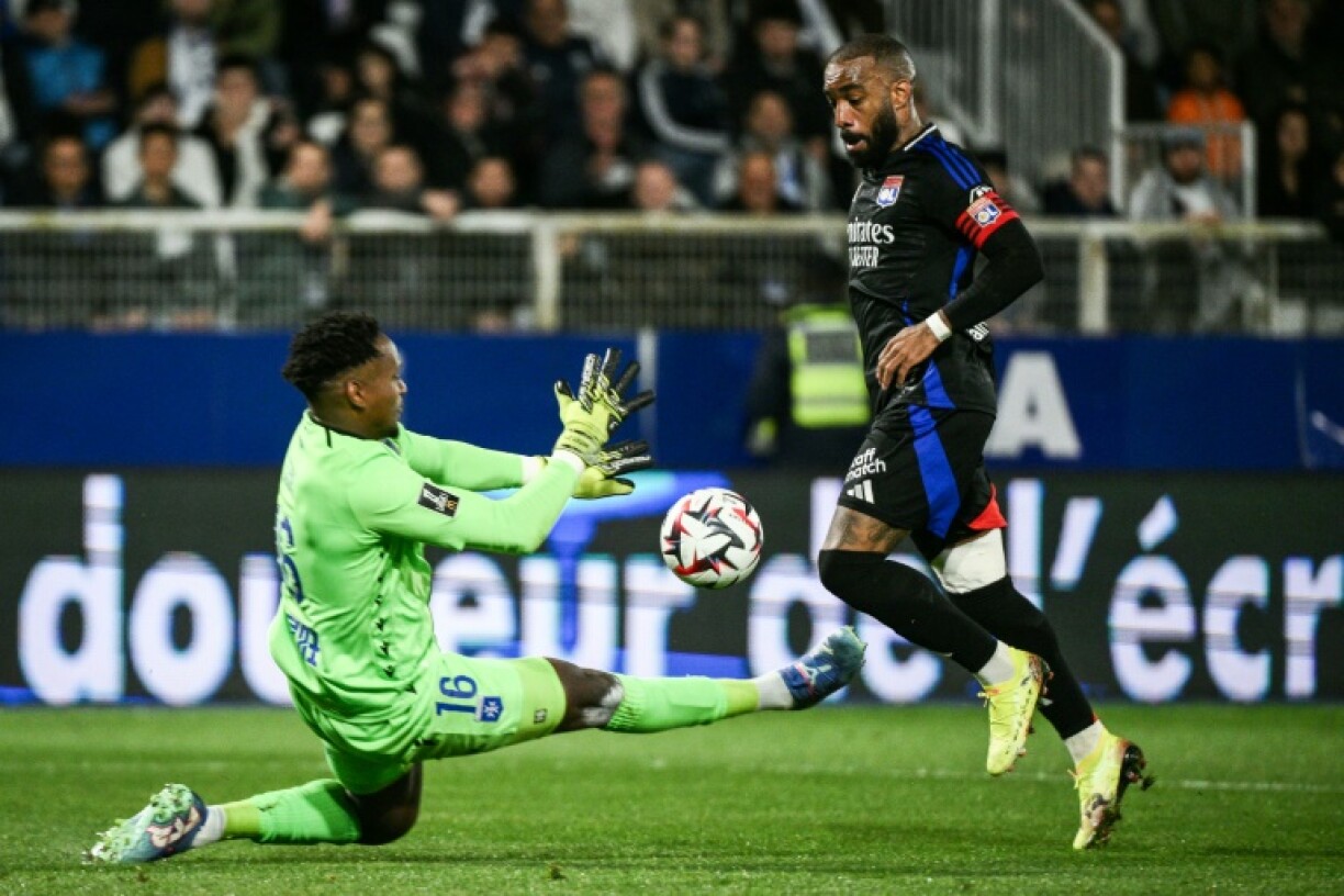 Auxerre goalkeeper Donovan Leon (L) fights for the ball with Lyon forward Alexandre Lacazette during Lyon's 3-1 win