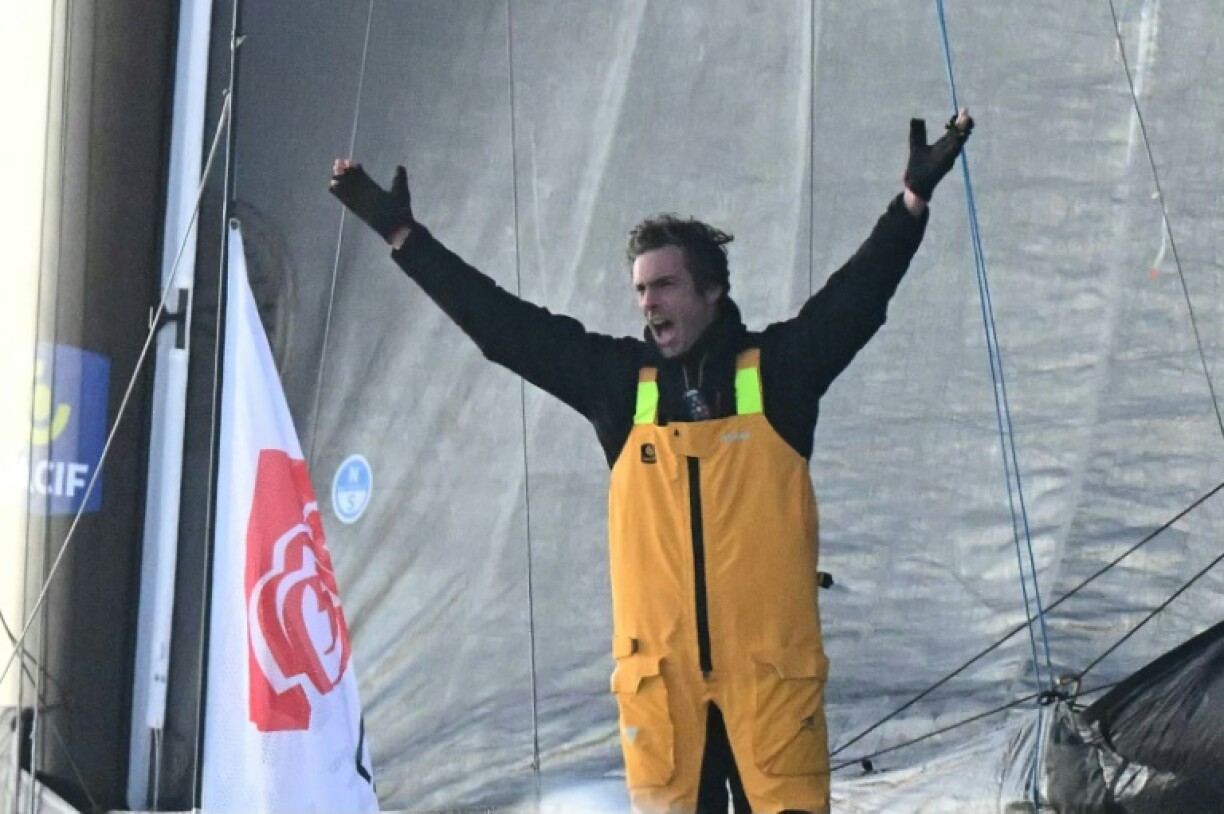 Charlie Dalin lifts his arms in triump after winning the Vendee Globe