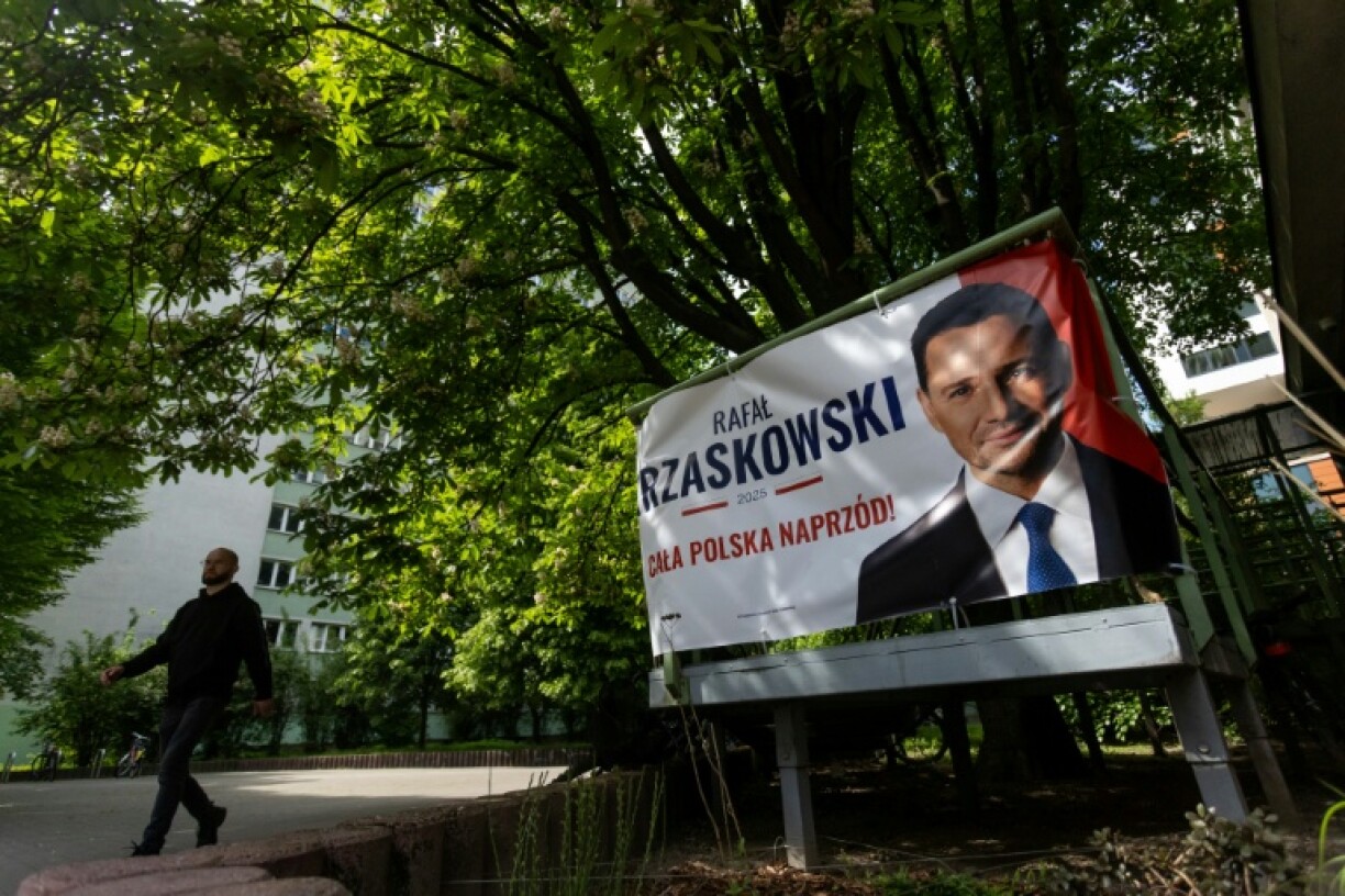 A man walks past a campaign banner featuring Rafal Trzaskowski in Warsaw ahead of Poland’s June 1, 2025 presidential runoff. Trzaskowski, the centrist mayor of Warsaw, has said he would back measures to allow abortion until the 12th week. He faces conservative historian Karol Nawrocki in a race seen as a referendum on Poland’s liberal shift.