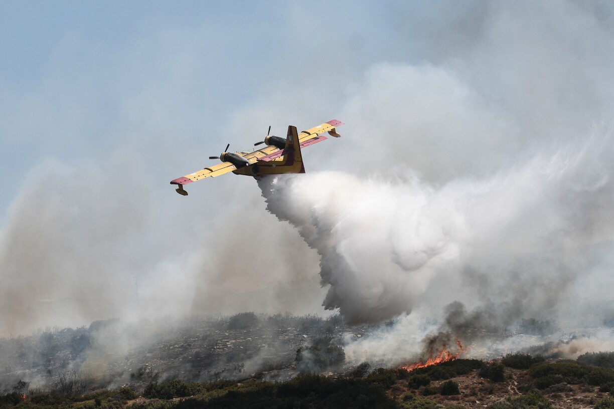 A Canadair CL-415 drops water onto a wildfire near the city of Volos, central Greece, on July 27, 2023. Greek fire crews on July 27 scrambled to put out wildfires raging for two weeks around the country that left five dead before strong winds forecast for the day rekindle blazes.