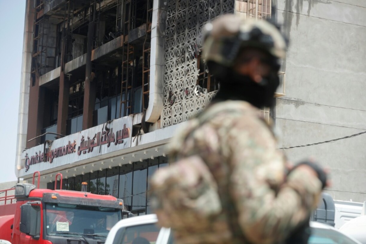 A member of the Iraqi security forces stands guard near the mall that was gutted by the deadly fire