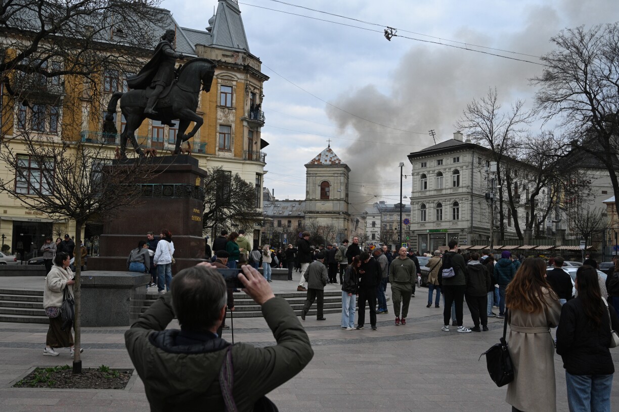 People look at smoke rising from a burning building following a Russian drone attack in Lviv on 24 March 2026, amid the Russian invasion of Ukraine.