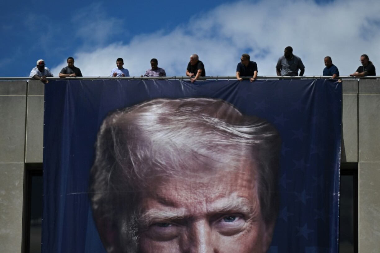 Workers hang a large photo of US President Donald Trump on the facade of the Department of Labor headquarters in Washington