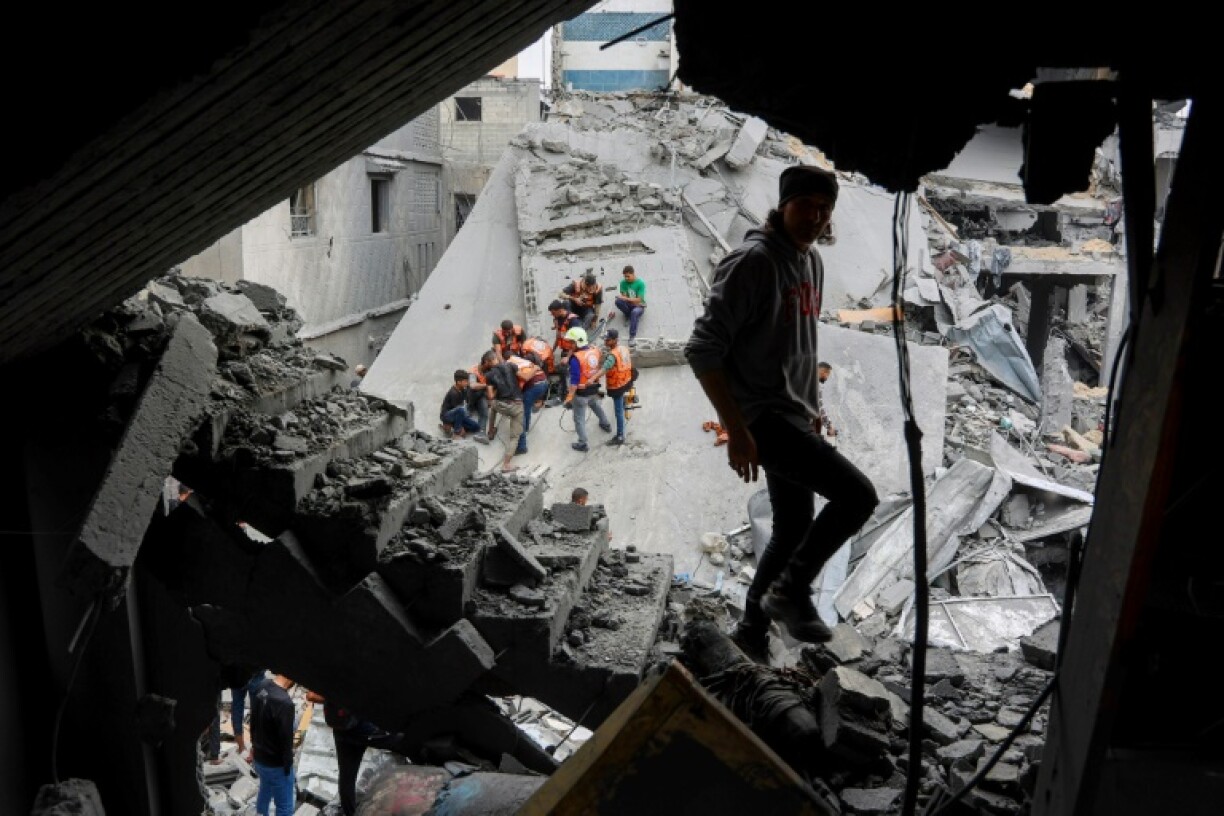 A man walks amids the rubble of a building as Palestinian rescuers work at the site of an Israeli strike on a residential area in Gaza City's Shujaiyya neighbourhood