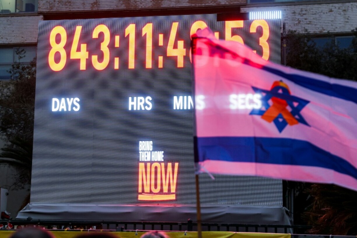 Un drapeau israélien orné d'un ruban jaune devant l'horloge comptabilisant les jours, les minutes et les secondes écoulées depuis l'enlèvement d'otages israéliens vers la bande de Gaza lors des attaques du 7 octobre 2023, à Tel-Aviv, le 27 janvier 2026
