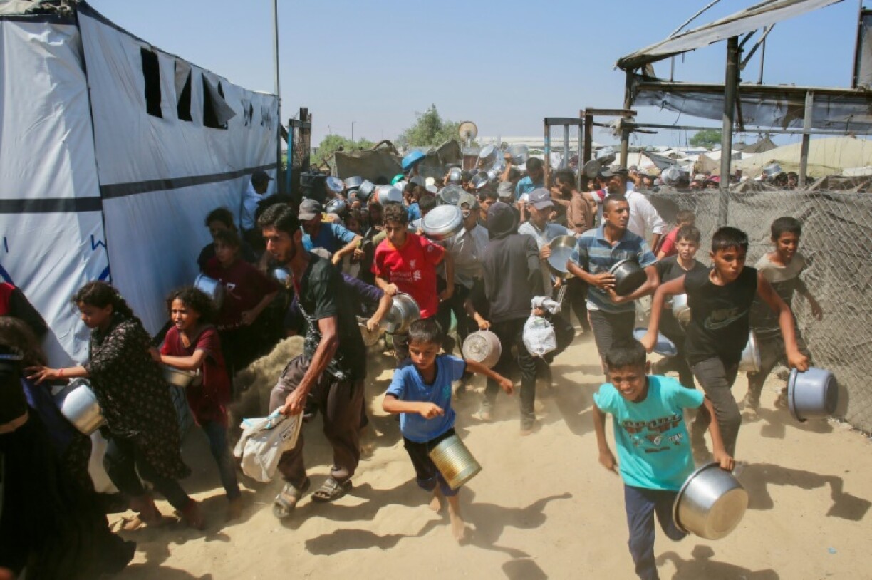 Palestinians rush to queue at a charity kitchen in Gaza, where the population has been experiencing acute food shortages for months