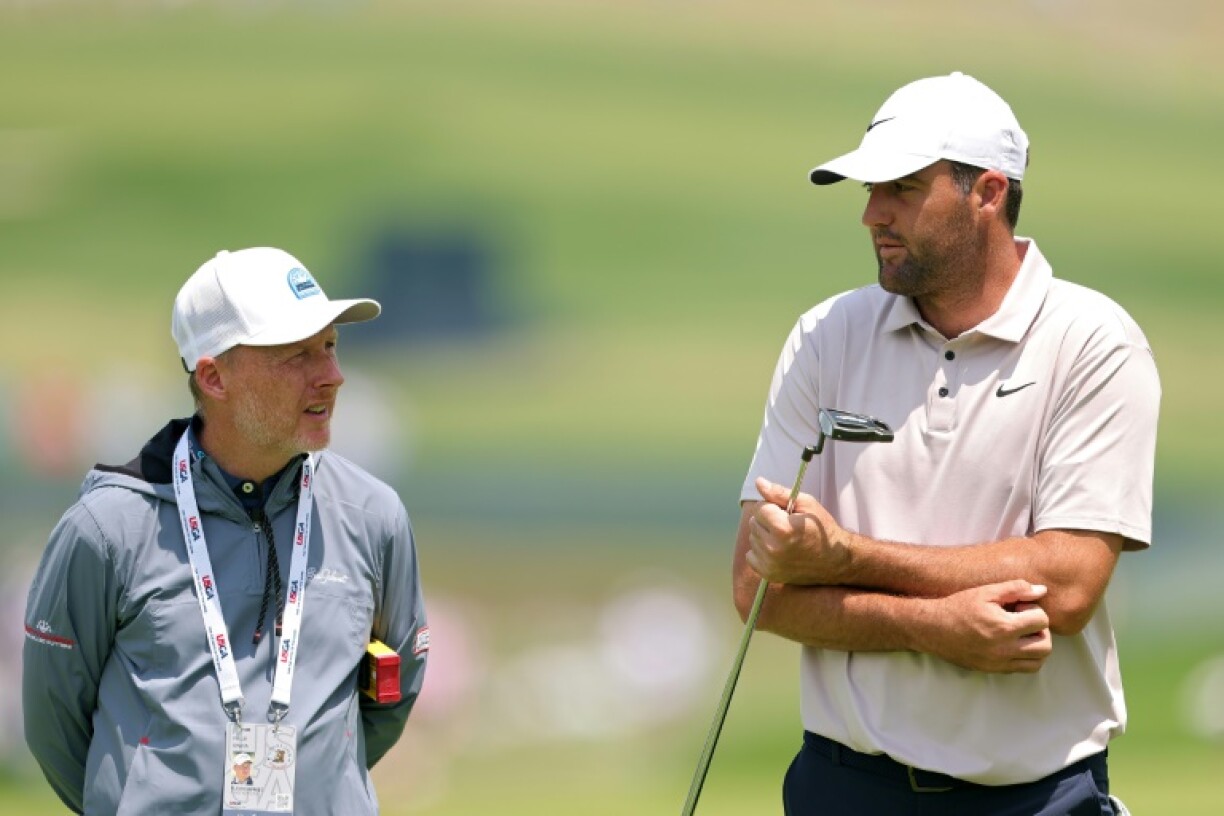World number one Scottie Scheffler of the United States, right, talks with coach Phillip Kenyon on the putting green during a practice round ahead of the 125th US Open at Oakmont