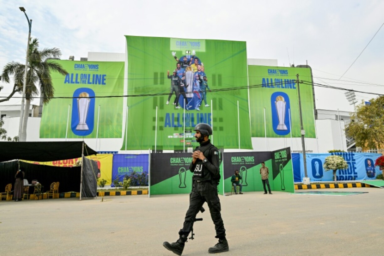 A Pakistani police commando walks past posters displayed ahead of the Champions Trophy in Karachi