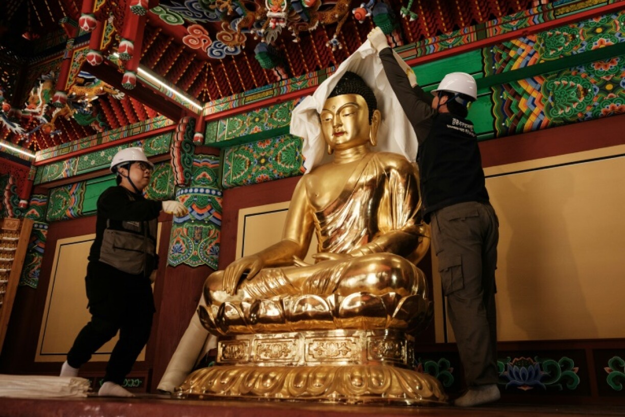 Members of the Gyeongbuk Seobu Cultural Heritage Care Center wrap a Buddha statue with cotton cloth and a fire-retardant blanket
