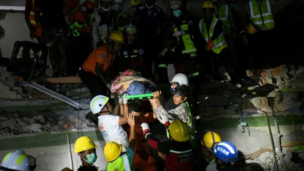 Des secouristes transportent une victime piégée sous les décombres de l'immeuble Sky Villa Condominium détruit à Mandalay, en Birmanie, le 30 mars 2025