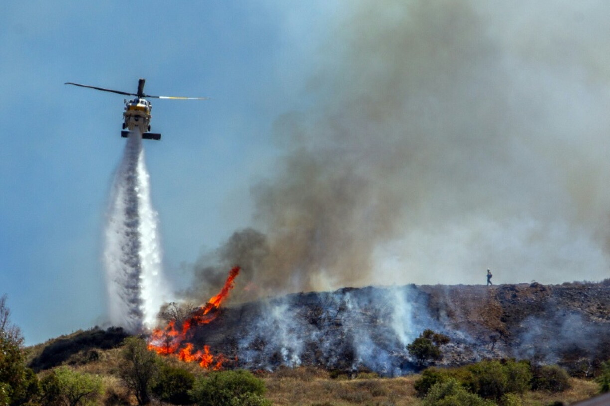 Un hélicoptère largue de l'eau sur les flammes du