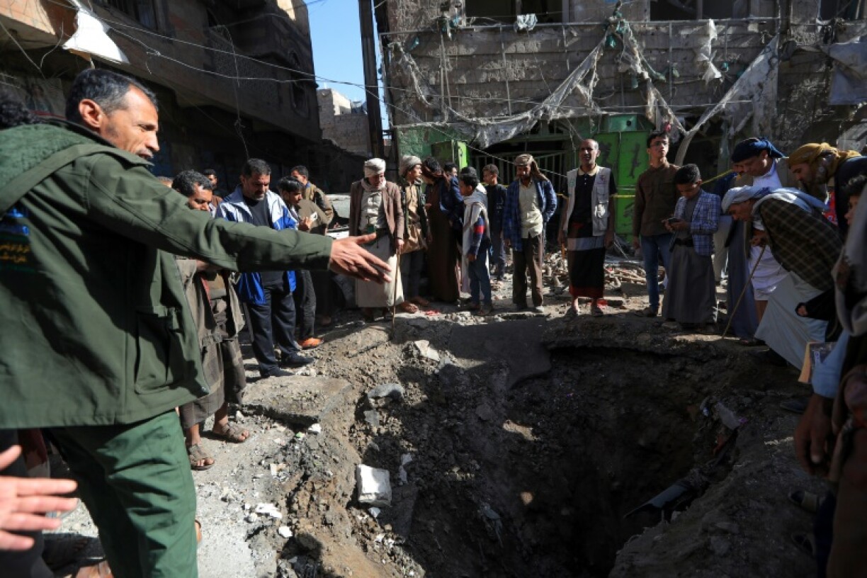 People assess the damage caused by a US air strike in Sanaa