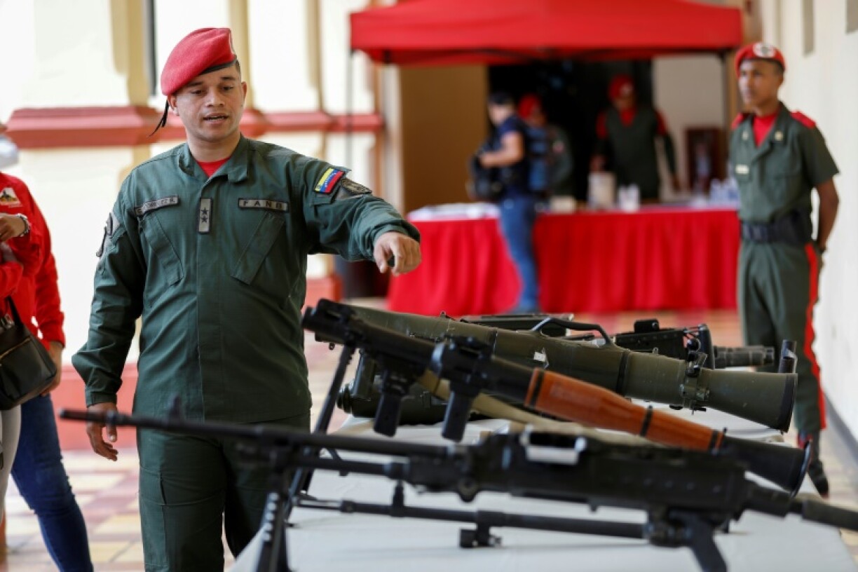 Un membre de la garde présidentielle vénézuélienne montre des armes lors d'une cérémonie à l'intention des personnes qui se sont inscrites pour rejoindre les forces militaires lors d'une campagne nationale d'enrôlement lancée par le président Nicolas Maduro, le 23 août 2025 à Caracas