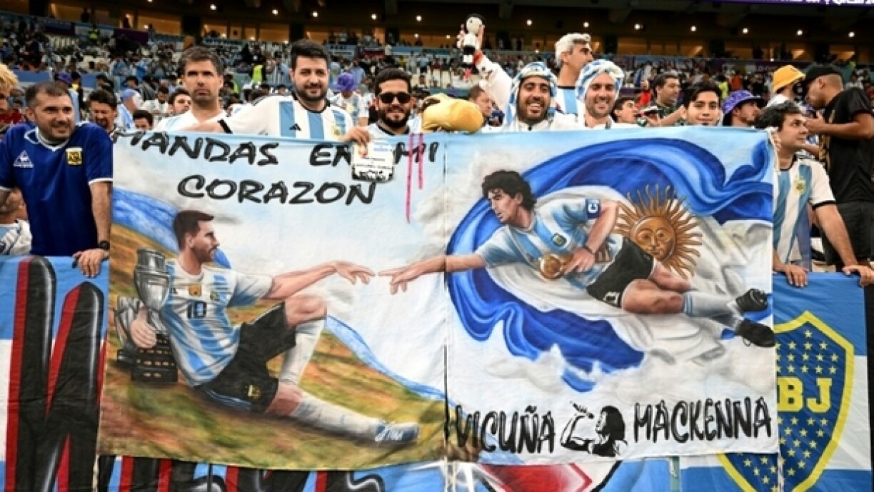 Des supporters argentins portent une bannière à l'effigie des légendes Diego Maradona et Lionel Messi, lors du match du Mondial, le 9 décembre 2022 à Doha