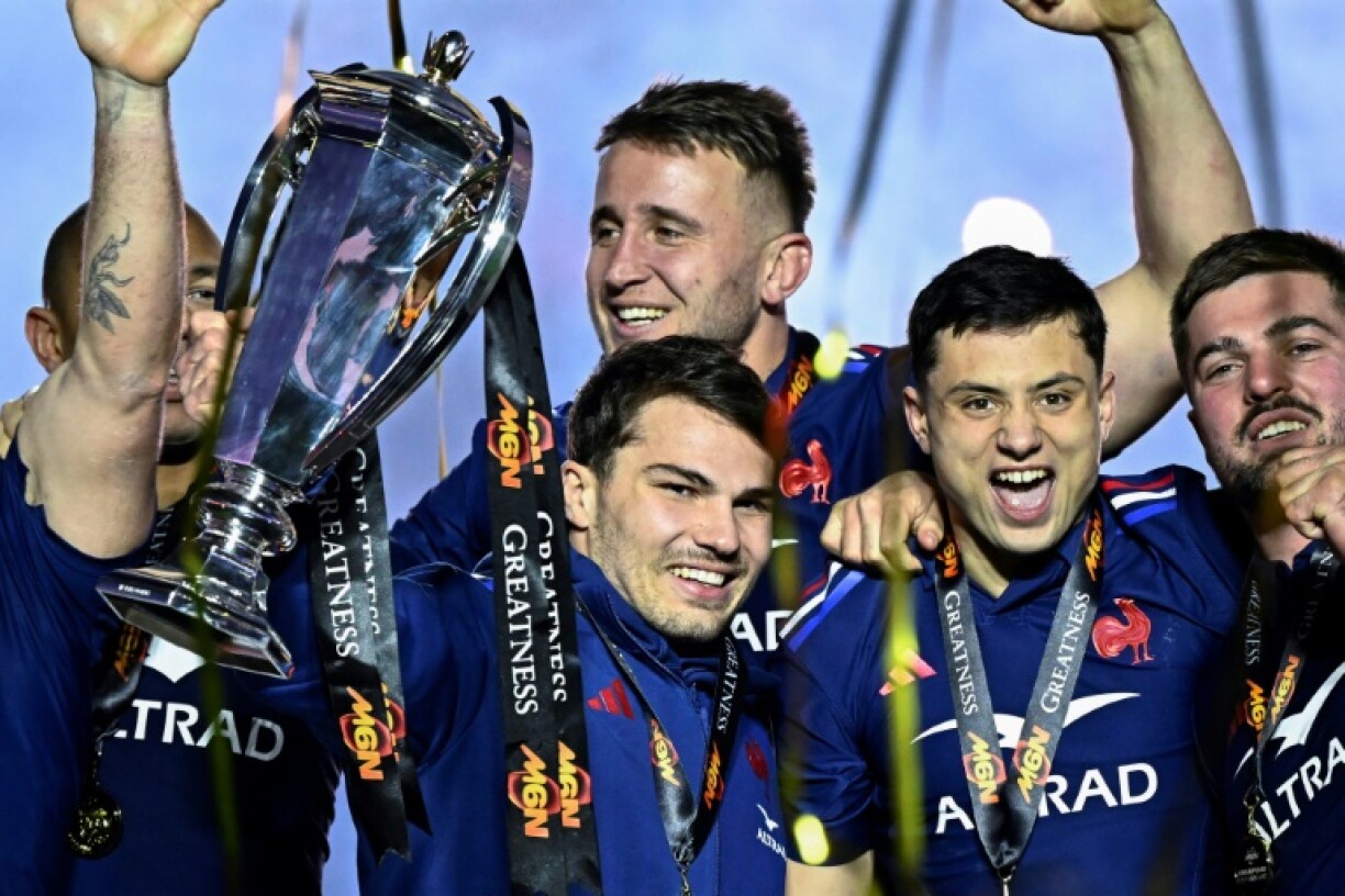 Antoine Dupont (C) holds the Six Nations trophy next to France's winger Louis Bielle-Biarrey (2R)
