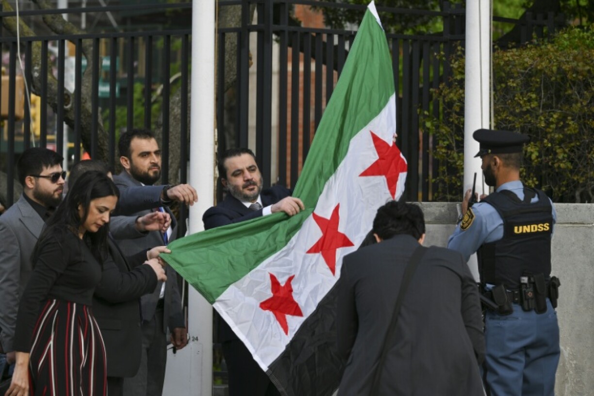 Syrian Foreign Minister Asaad al-Shaibani raises the new Syrian flag during a ceremony at United Nations headquarters in New York