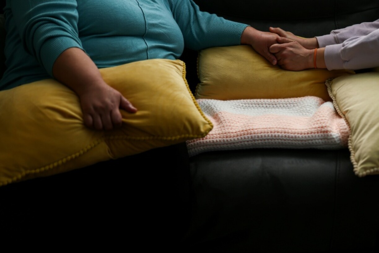 Ana (à gauche), une habitante mexicaine de Minneapolis, tend la main à une amie à son domicile le 31 janvier 2026, alors que la ville est le théâtre depuis plusieurs semaines de raids de la police de l'immigration (ICE)