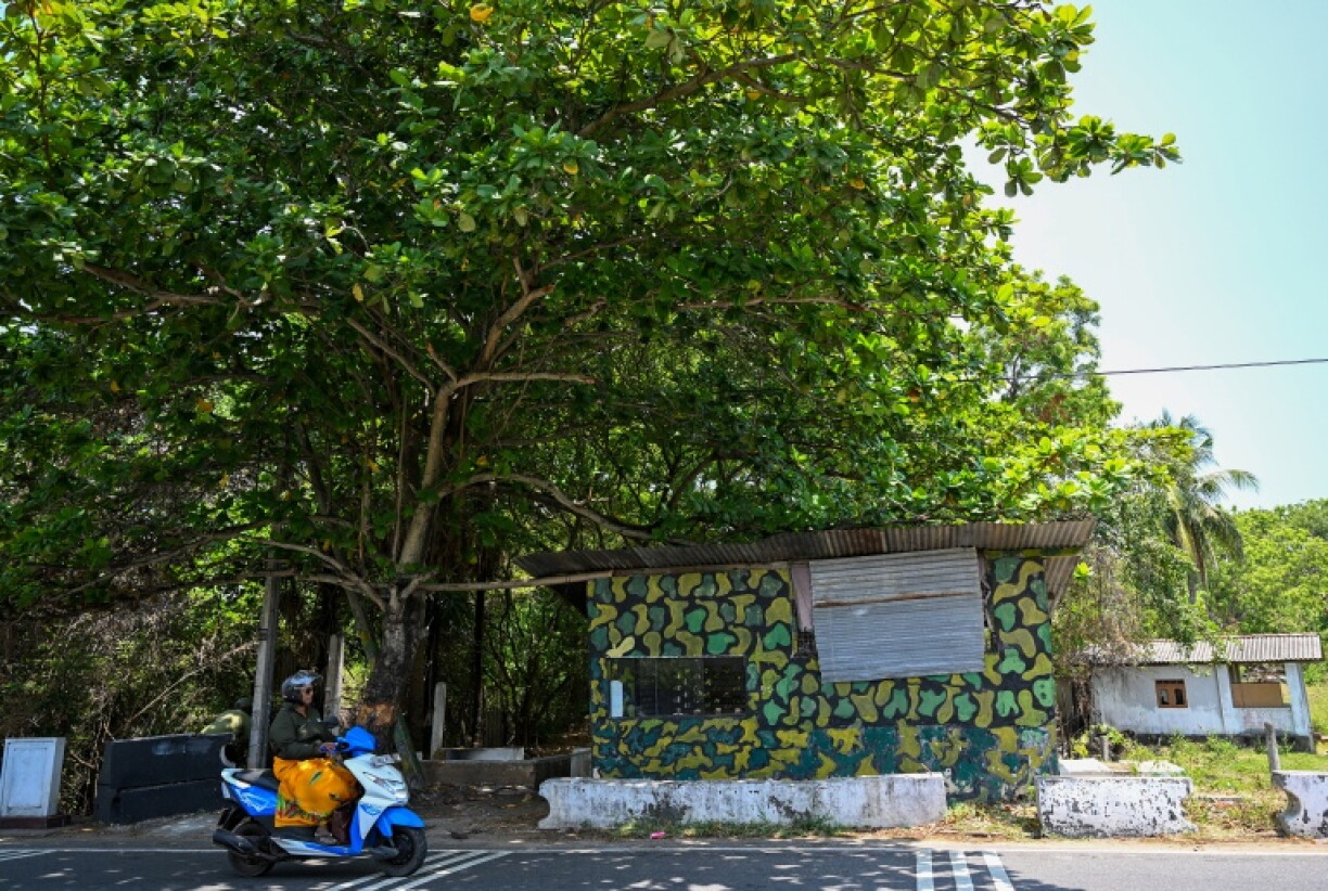A woman rides a scooter past an uninhabited army settlement on a disputed land at Batticaloa in Sri Lanka's Eastern Province