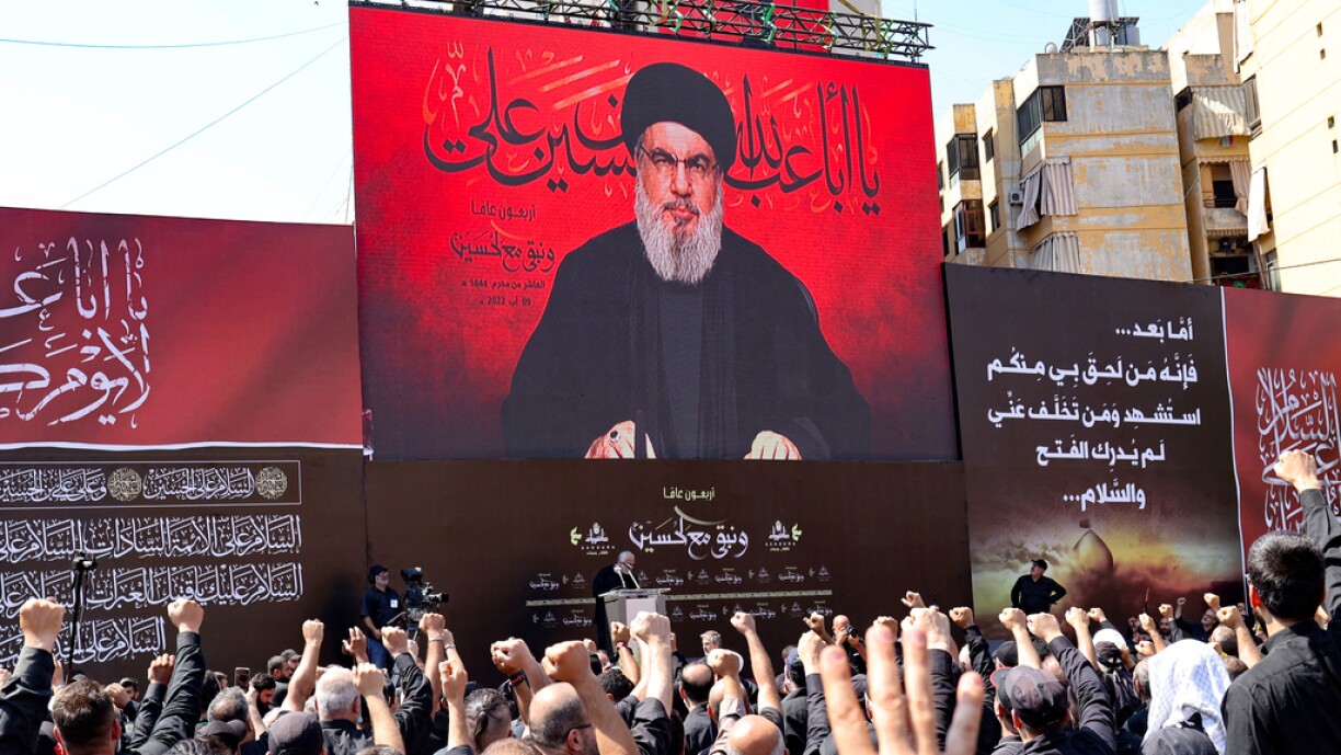Supporters of Lebanon's Hezbollah react as the group's leader Hassan Nasrallah addresses them through a giant screen in Beirut's southern suburbs on 9 August 2022.