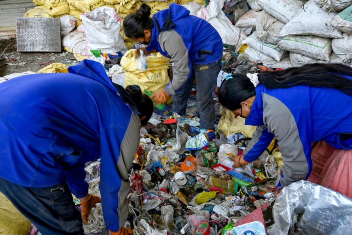 Des personnes trient les déchets récupérés sur les pentes de l'Everest pour les recycler à Katmandou, le 12 juin 2024 au Népal