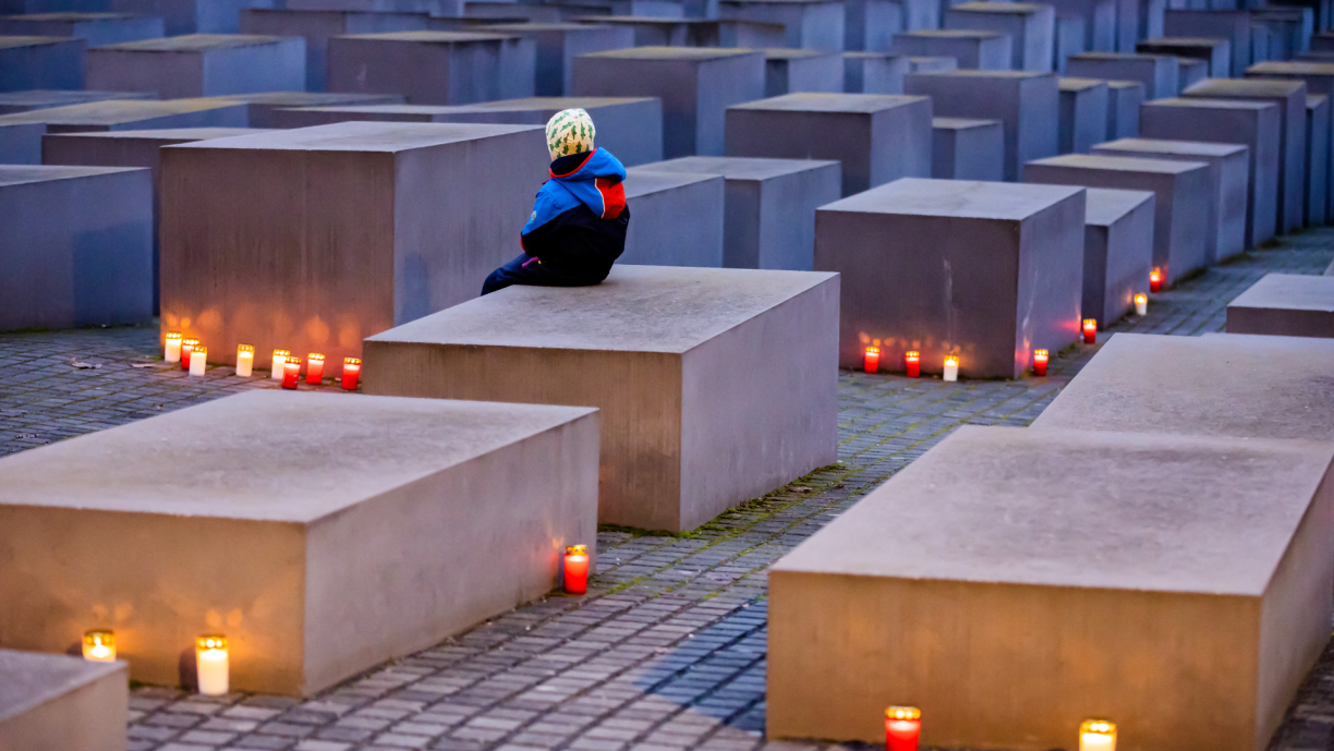 A child sits between candles at the Memorial to the Murdered Jews of Europe in Berlin on the eve of the International Day of Remembrance of the Victims of the Holocaust